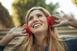 portrait de souriant femme, écoute à la musique sur rouge écouteurs photo