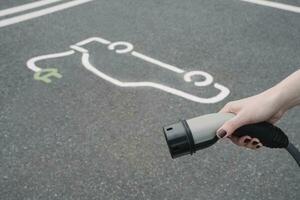 Allemagne, main de femme en portant prise de courant de électrique véhicule mise en charge station photo