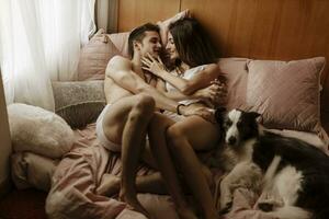 content Jeune couple et chien mensonge dans lit photo