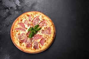 délicieuse pizza fraîche et croustillante du four avec jambon, fromage et basilic photo