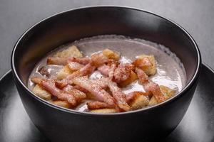 Soupe fraîche et délicieuse de purée chaude aux champignons et bacon dans une assiette noire photo