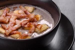 Soupe fraîche et délicieuse de purée chaude aux champignons et bacon dans une assiette noire photo