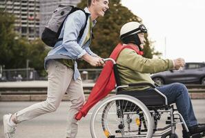 Jeune homme pousser Sénior homme séance dans une fauteuil roulant habillé en haut comme super-héros photo