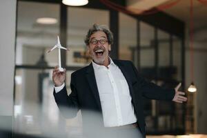 excité Sénior homme d'affaire avec vent turbine modèle dans Bureau photo