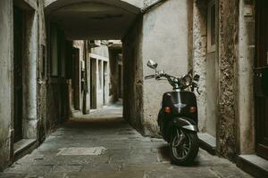 solitaire garé rétro scooter dans de face de un maison dans vieux vide étroit ruelle avec pierre route de historique ville de piran dans slovénie photo