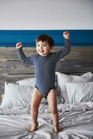 portrait de content bambin sauter sur lit photo