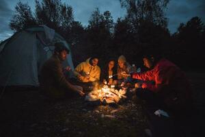 groupe de copains séance à une feu de camp, grillage guimauves photo