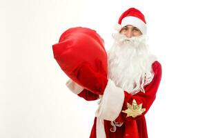 Père Noël claus permanent en haut sur blanc Contexte avec le sien sac plein de cadeaux photo