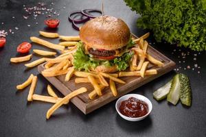 délicieux burger frais avec escalope de boeuf, tomates et laitue avec frites photo