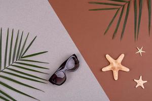 accessoires de plage, lunettes et chapeau avec coquillages et étoiles de mer sur fond coloré. fond d'été photo