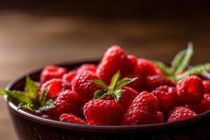 délicieuses framboises rouges juteuses fraîches sur une table sombre photo