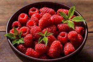 délicieuses framboises rouges juteuses fraîches sur une table sombre photo