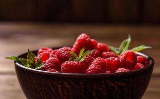 délicieuses framboises rouges juteuses fraîches sur une table sombre photo