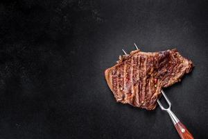 délicieux steak de boeuf frais juteux avec des épices et des herbes sur un fond de béton foncé photo