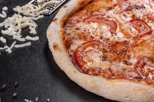délicieuse pizza italienne fraîche aux champignons et tomates sur fond de béton foncé photo
