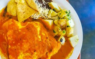 Oeufs d'omelette mexicaine haricots noirs pommes de terre nachos sur plaque blanche. photo