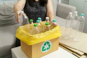 Accueil recycler éco vert zéro concept femme lancement vide Plastique bouteille dans recyclage poubelle avec Jaune des ordures Sacs à maison. photo