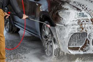 voiture sans contact lavage en libre-service. laver avec de l'eau et de la mousse. photo