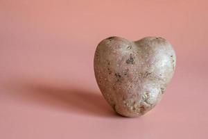 pommes de terre en forme de coeur sur fond rose. le concept d'agriculture, de récolte, de végétarisme. photo