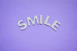 mot de sourire avec des lettres en bois sur le fond violet photo