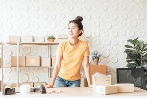 femme asiatique propriétaire d'entreprise travaillant à la maison avec une boîte d'emballage sur le lieu de travail - achat en ligne PME entrepreneur ou concept de travail indépendant photo