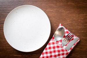 assiette ou plat vide avec couteau, fourchette et cuillère sur fond de carreaux de bois photo