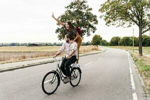 content Jeune couple équitation ensemble sur un vélo sur pays route photo