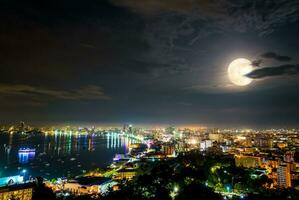 plein lune au dessus Pattaya ville à nuit, Thaïlande photo