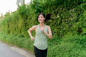 en forme asiatique Jeune femme le jogging dans parc souriant content fonctionnement et profiter une en bonne santé Extérieur mode de vie. femelle joggeur. aptitude coureur fille dans Publique parc. en bonne santé mode de vie et bien-être étant concept photo