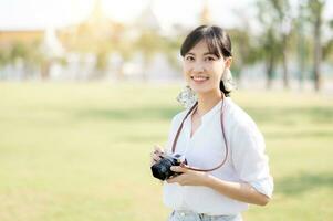 portrait de asiatique femme voyageur en utilisant caméra. Asie été tourisme vacances concept avec le grandiose palais dans une Contexte à Bangkok, Thaïlande photo