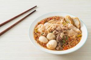 nouilles au porc et boulettes de viande dans une soupe épicée ou nouilles tom yum à l'asiatique photo