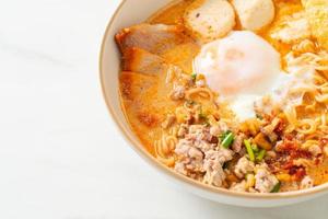 nouilles instantanées au porc et boulettes de viande dans une soupe épicée ou nouilles tom yum à l'asiatique photo