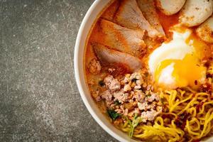 nouilles aux œufs avec porc et boulettes de viande dans une soupe épicée ou nouilles tom yum à l'asiatique photo