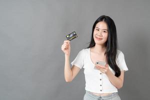 jeune femme asiatique utilisant un téléphone avec une main tenant une carte de crédit - concept de magasinage en ligne photo