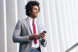 homme d'affaires noir utilisant un smartphone près d'un immeuble de bureaux photo