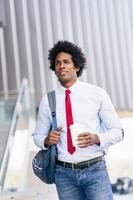 homme d'affaires noir souriant avec un verre à emporter. photo