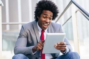 homme d'affaires noir à l'aide d'une tablette numérique assis photo