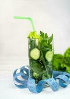 Ingrédients pour une en bonne santé vert smoothie dans le verre et mesure ruban sur le tableau. désintoxication boisson concept. en bonne santé aliments. photo