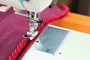 couture machine. le processus de couture une décoratif corde de rouge tissu. photo