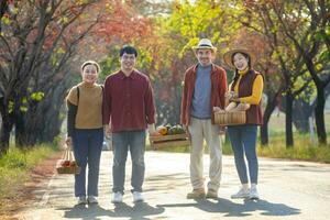 content asiatique agriculteur famille avec Sénior parent sont porter produire récolte avec fait maison organiques pomme, écraser et citrouille avec tomber Couleur de érable arbre pendant l'automne saison pour agriculture concept photo