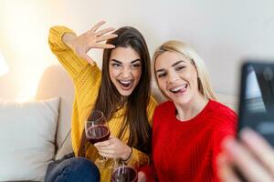 excité copains prise selfie et en riant. intérieur coup de deux émotif caucasien filles. deux adulte femme fabrication selfies avec marrant visages. deux femelle copains prise une selfie photo