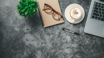 Haut voir, foncé Bureau bureau avec portable ordinateur, tasse de café, stylo, monocle et carnet de notes, copie espace, moquer en haut. photo