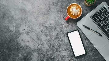 Haut voir, foncé Bureau bureau avec portable ordinateur, Vide écran intelligent téléphone, tasse de café et stylo, copie espace, moquer en haut. photo