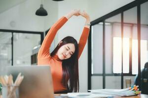 affaires femme relaxant avec mains derrière sa tête et séance sur un Bureau chaise photo