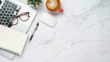 Haut voir, blanc Bureau bureau avec portable ordinateur, tasse de café, stylo, Souris et carnet de notes, copie espace, moquer en haut. photo