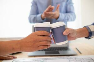 équipes ingénieurs, architectes et réel biens investisseurs baratté plus de tasse de chaud café à féliciter leur leur réussi projet conception dans budget. chaud café choc concept à célébrer dans Bureau photo