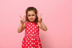 joyeux magnifique 4 ans anniversaire bébé fille dans été robe faire des gestes, Faire la victoire signe avec doigt. adorable enfant montrant nombre deux. photo