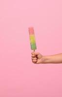 en bonne santé végétalien la glace crème popsicle dans main de une bébé fille avec rose mur à Contexte avec copie espace . été dessert et de bonne humeur été ambiance concept photo