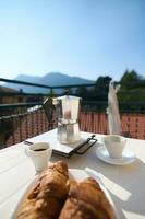 concentrer sur un italien percolateur, moka brasseur sur le table avec servi petit déjeuner sur le balcon dans italien village photo