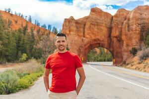 Jeune caucasien homme dans Contexte de Naturel pierre cambre pont dans le rouge canyon nationale parc dans Utah, Etats-Unis photo